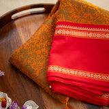 Devi Energised Cotton Saree – Golden Orange with Olive Green Floral Motifs & Vibrant Red Traditional Border